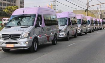 #PraCegoVer: Imagem de oito vans do serviço Atende+, em cores lilás e prata, em circulação.