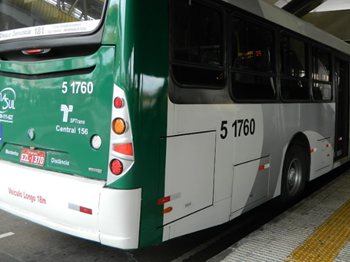 #pracegover traseira do ônibus da área cinco cor verde ao lado de plataforma com piso tatil amarelo