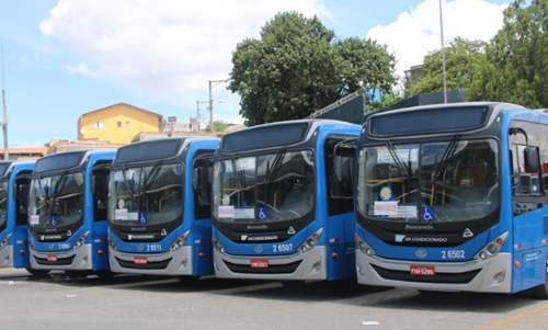 #PraCegoVer: a imagem mostra a frente de alguns ônibus azuis estacionados na garagem.