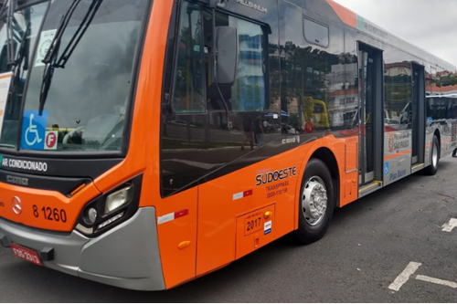 #PraCegoVer: a imagem mostra a lateral de um ônibus laranja estacionado.