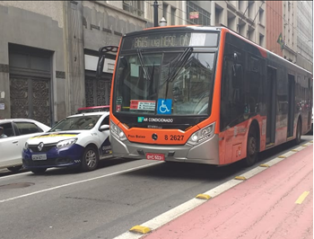 #pracegover ônibus da linhas 8615 perto de ciclofaixa e predios