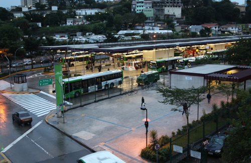 #pracegover imagem que mostra o terminal Pirituba de cima, tem ônibus saindo e alguns parados perto das plataformas a avenida com um carro e a noite chegando