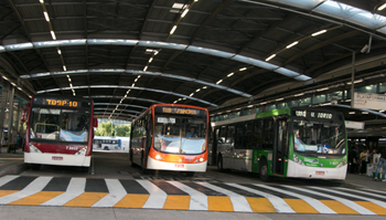 #pracegover três ônibus, sendo um da área oito, outro da área sete e outro da área um saindo do Terminal Pinheiros, com faixa de pedestres na frente