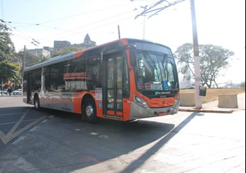 #pracegover ônibus da área oito cor laranja em uma rua com poste ao lado