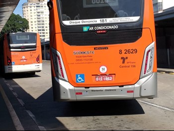 #pracegover traseira de dois ônibus da área oito da cor laranja dentro de um Terminal