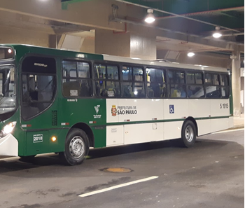 #PraCegoVer: Imagem noturna de um coletivo de cor verde escura localizado no interior do Terminal Vila Prudente, na Zona Leste da cidade.