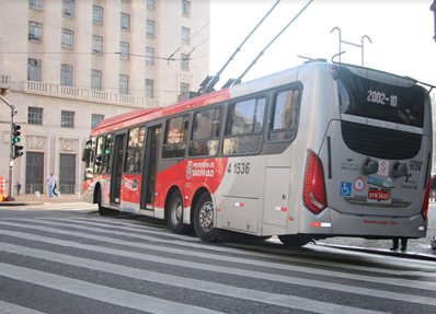#PraCegoVer: Imagem da traseira de um trólebus da linha 2002/10, em operação, subindo ladeira na região central.
