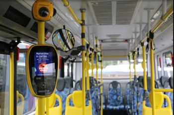 #PraCegoVer: A imagem mostra o interior de um ônibus com o foco no validador.