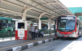 #pracegover ônibus dentro do terminal sapopemba com o letreiro sentido teotônio vilela com cabine de fiscalização e motoristas ao lado