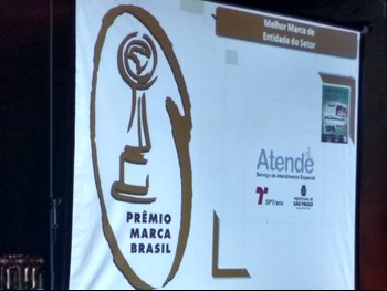 #PraCegoVer: Imagem do telão que aponta o momento em que o Atende+ é premiado como Melhor marca de entidade do setor