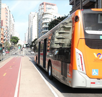 #PraCegoVer: Imagem de um veículo de cor laranja, que atende a Zona Sudoeste da cidade, circulando próximo a uma ciclovia