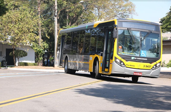 #PraCegoVer: Imagem de um ônibus de cor amarela, realizando uma curva acentuada em operação matutina