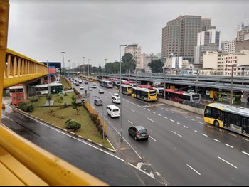 #pracegover ônibus dentro de terminal e ponte amarela para travessia
